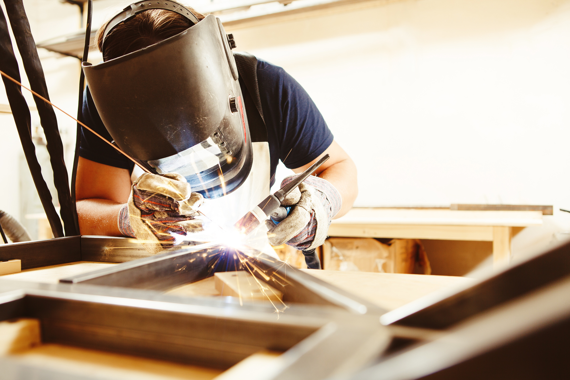 Male in face mask welds with argon-arc welding